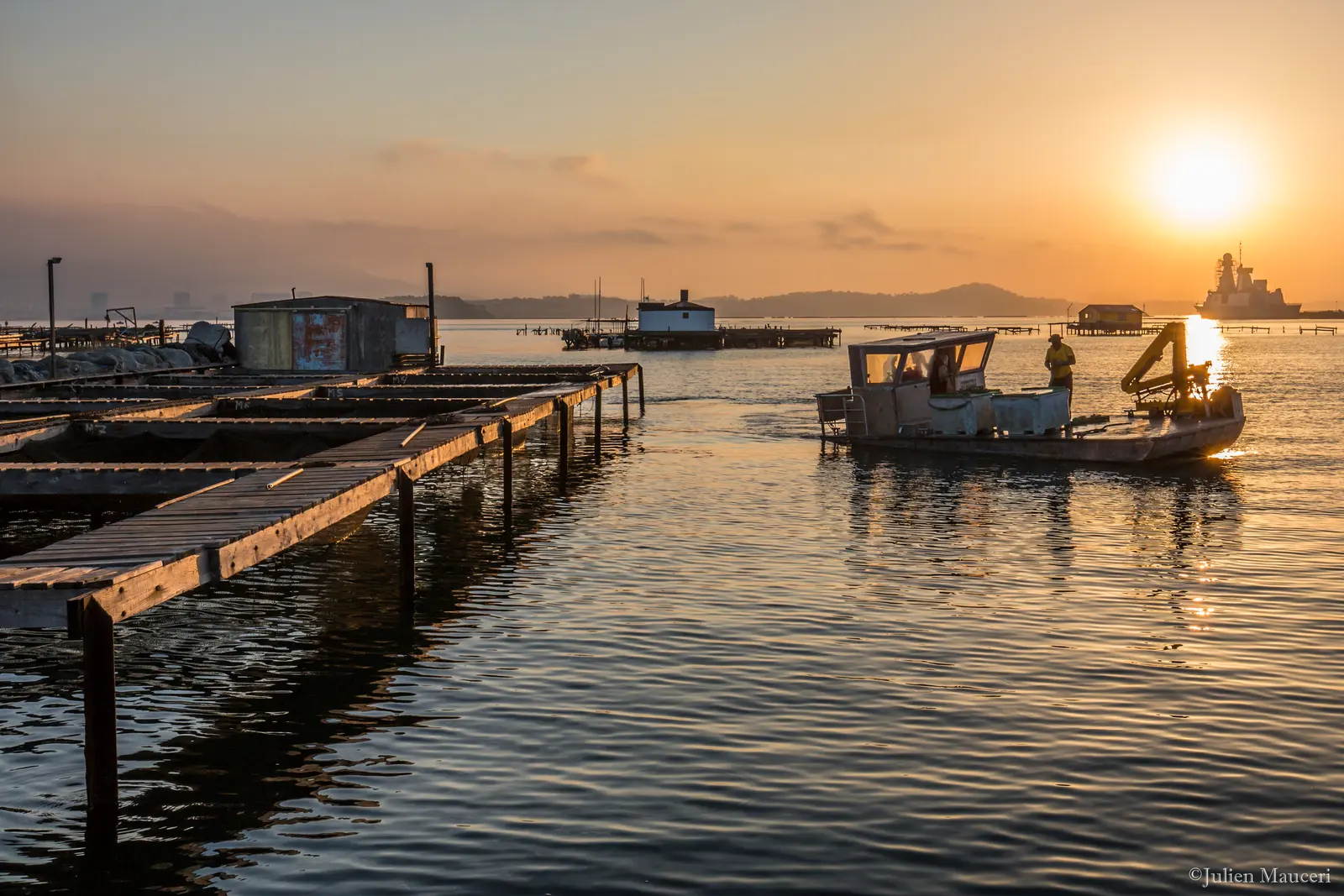 Lever du soleil sur les pontons de la ferme et un bateau de travail dans la baie